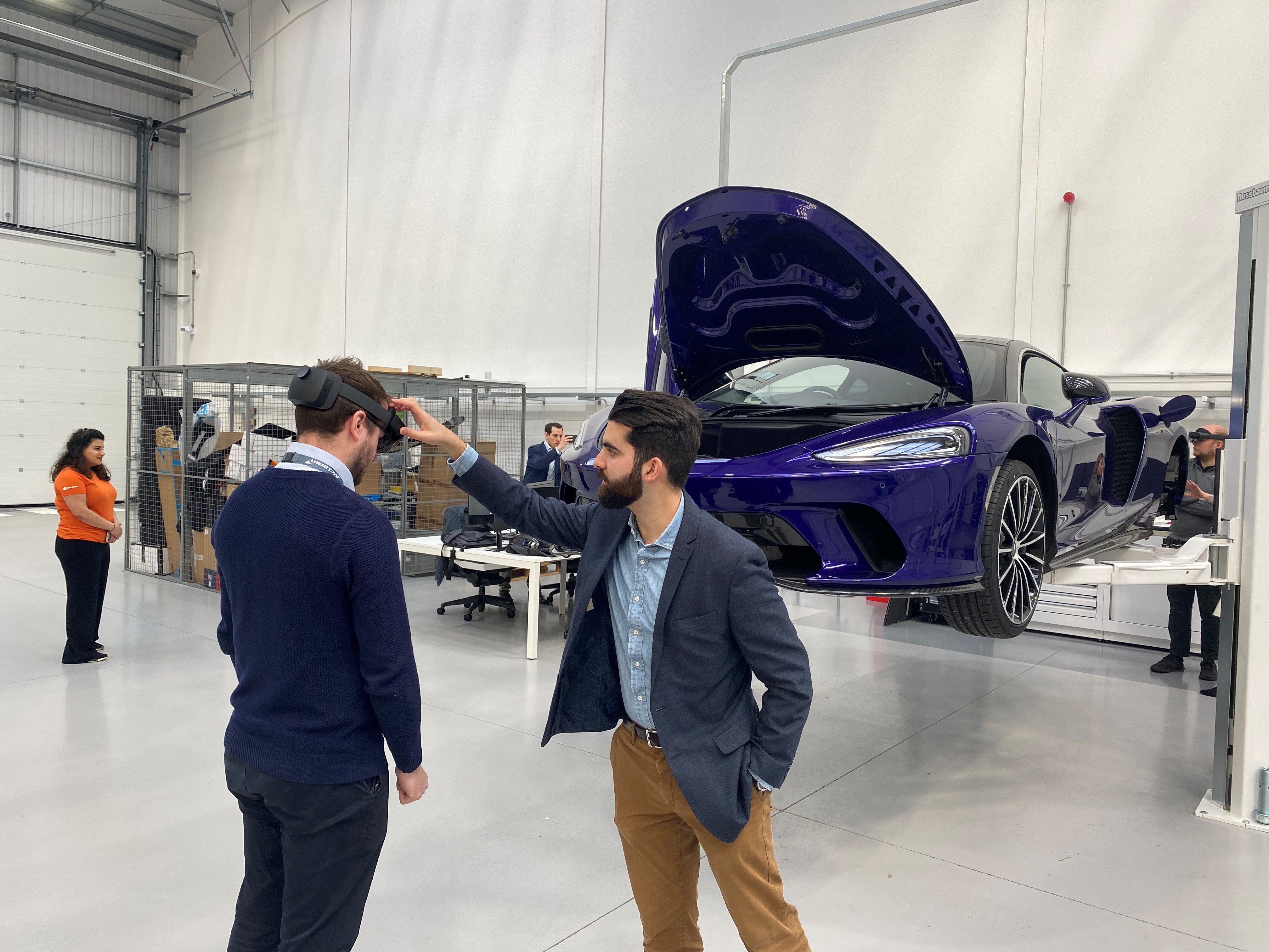 Alex Karim at McLaren demonstrating technology near a sports car